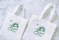 Two weiß tote Tüten mit green Branding on a light gray background