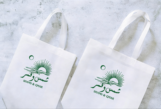 Two white tote bags with green branding on a light gray background