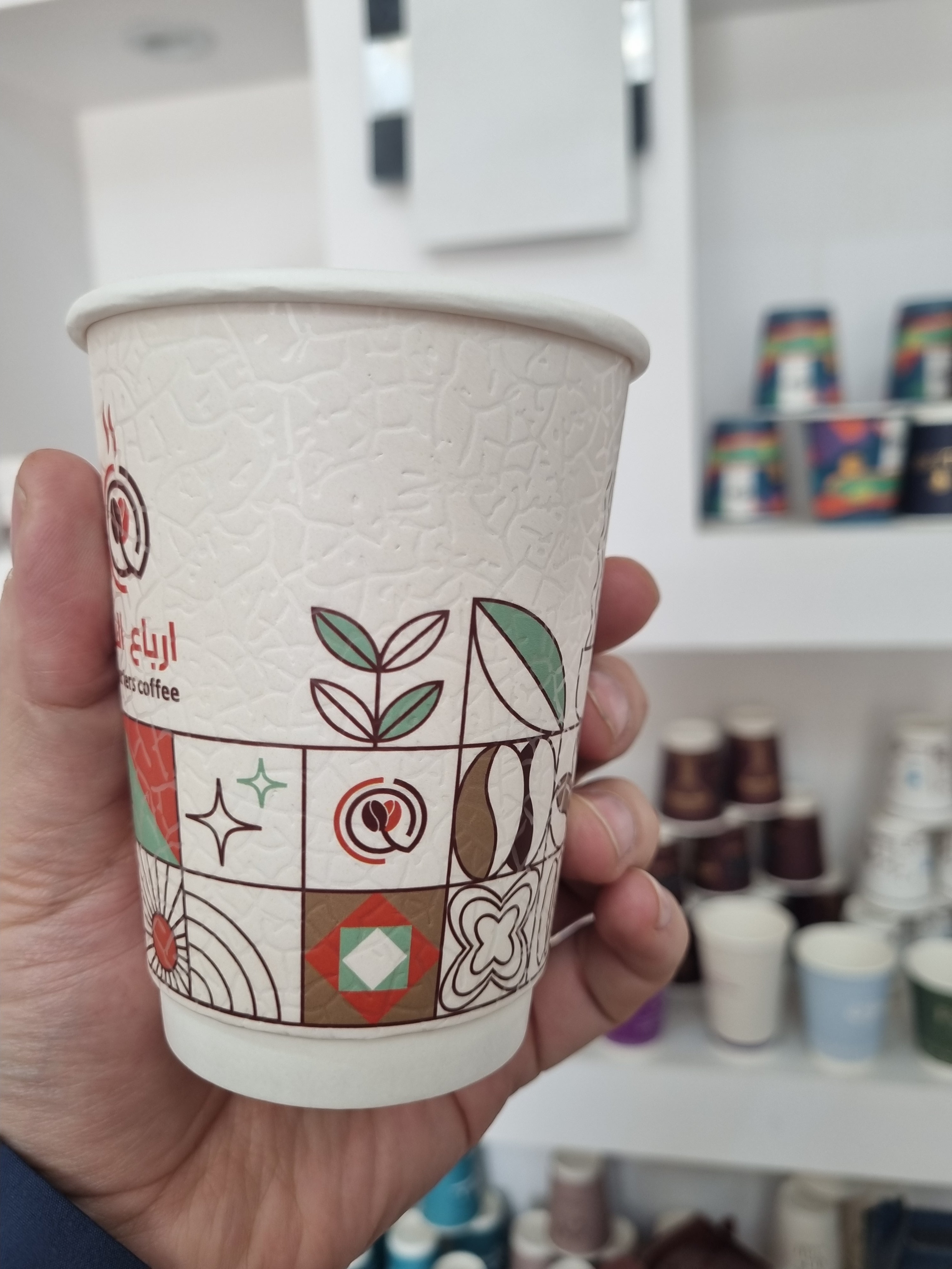 Gobelet à café écologique en papier avec des motifs géométriques colorés, idéal pour les boissons chaudes.