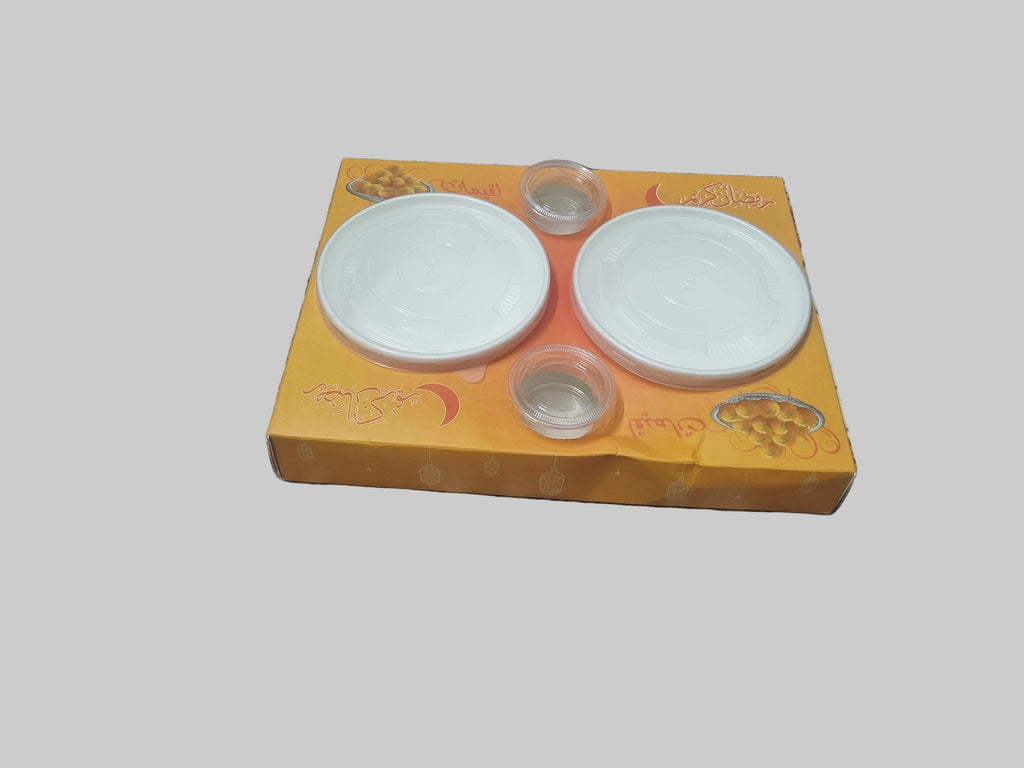 Two white ceramic plates on a yellow box with floral design on a patterned fabric background