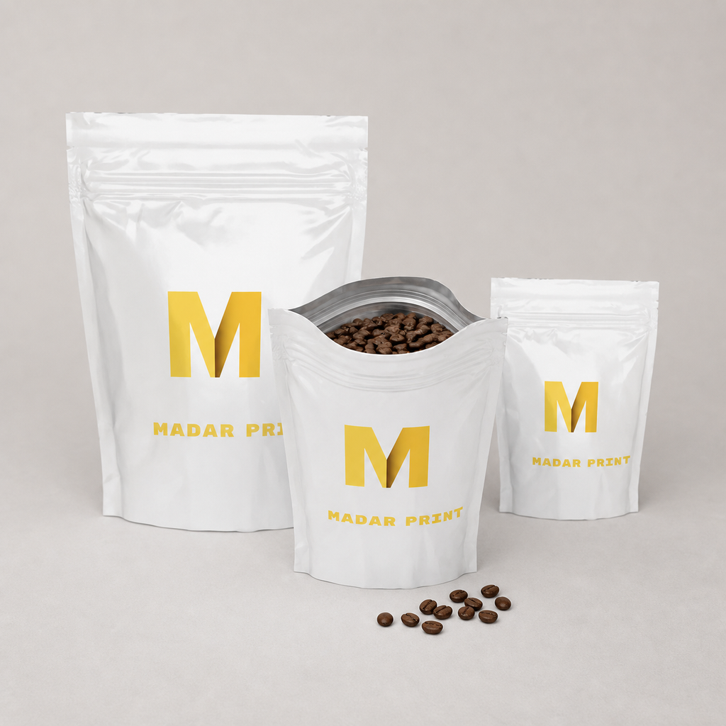 Three sizes of printed coffee pouches with the medium pouch open and filled with roasted beans
