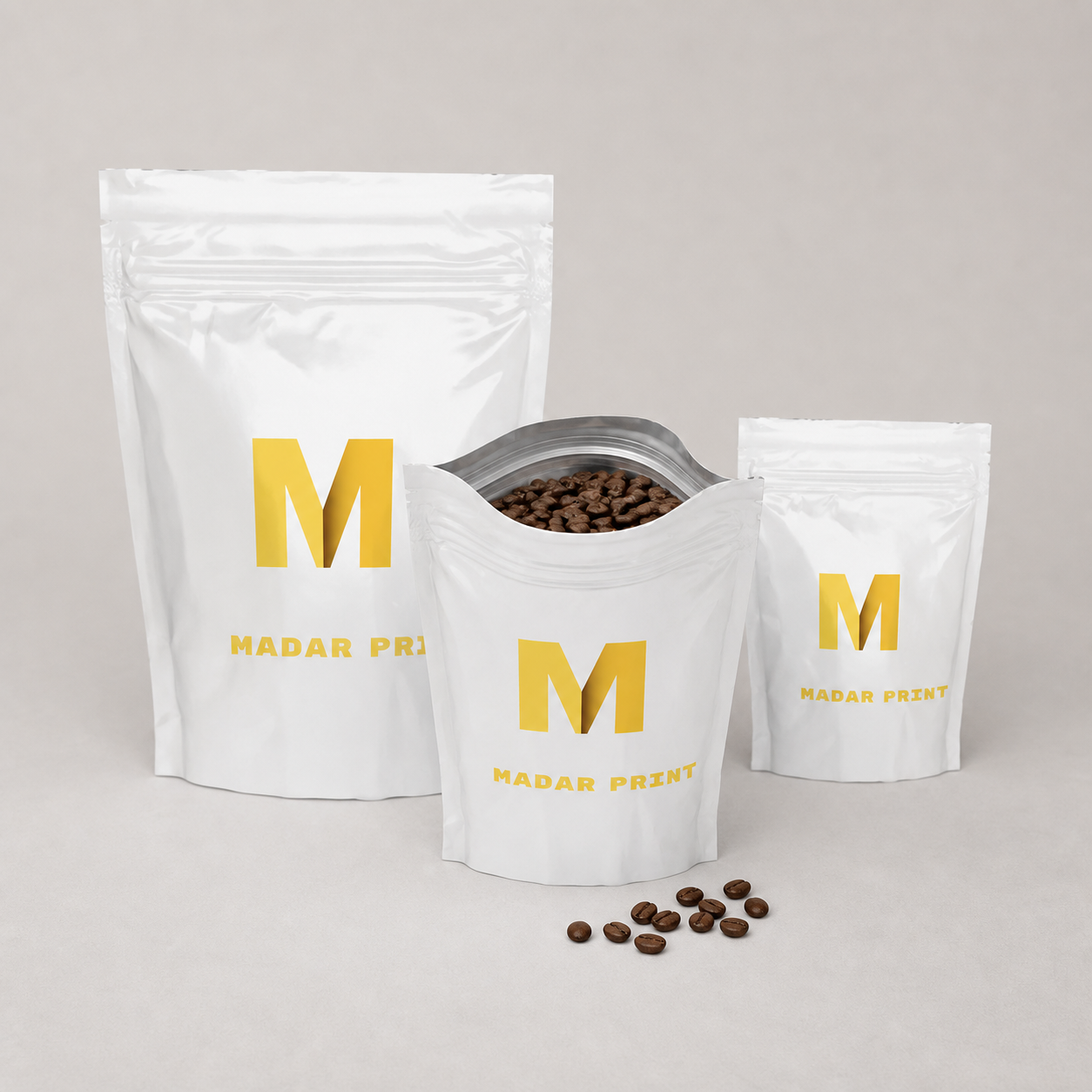 Three sizes of printed coffee pouches with the medium pouch open and filled with roasted beans
