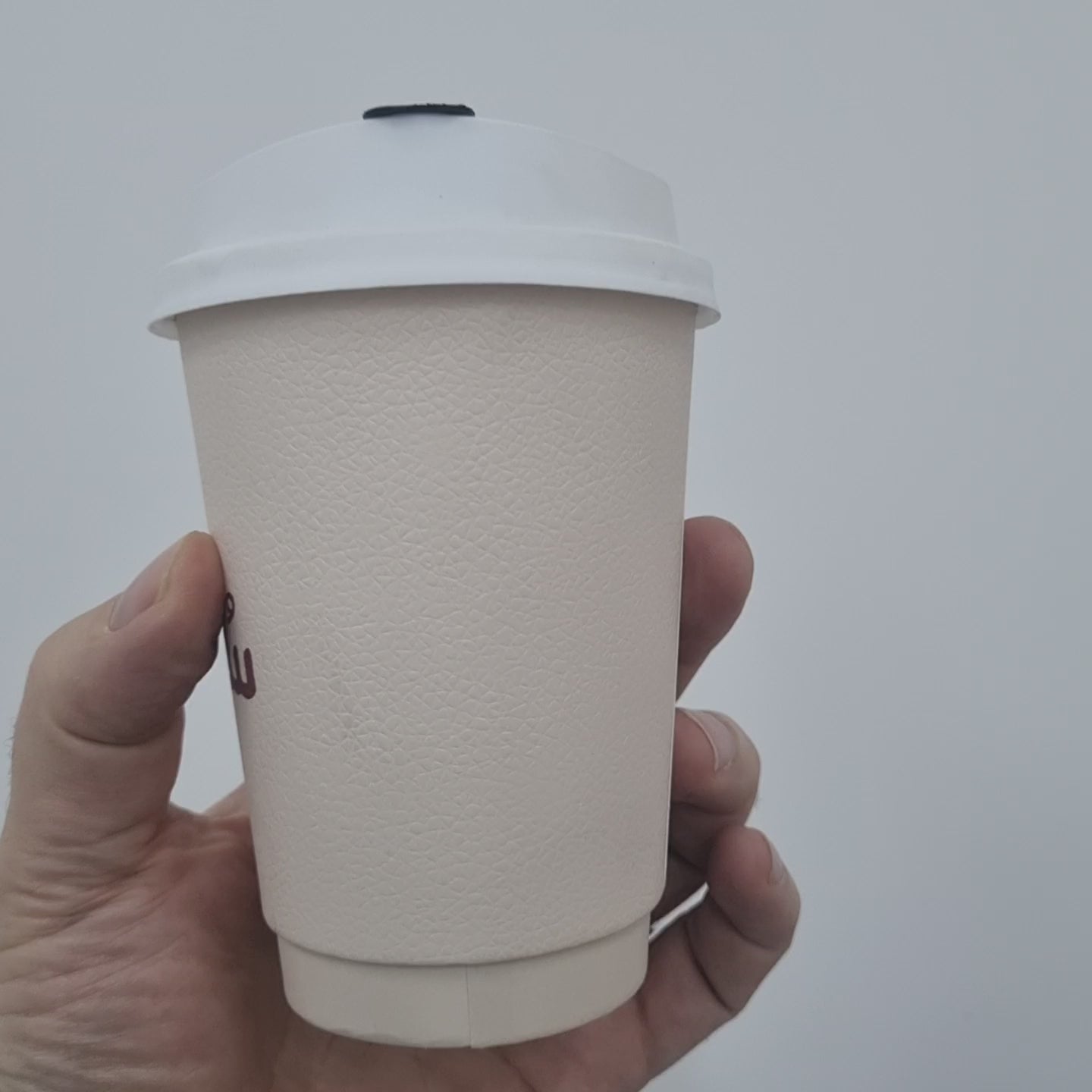 Eco-friendly blush pink coffee cup with a white lid, perfect for hot beverages.
