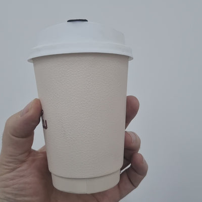 Eco-friendly blush pink coffee cup with a white lid, perfect for hot beverages.